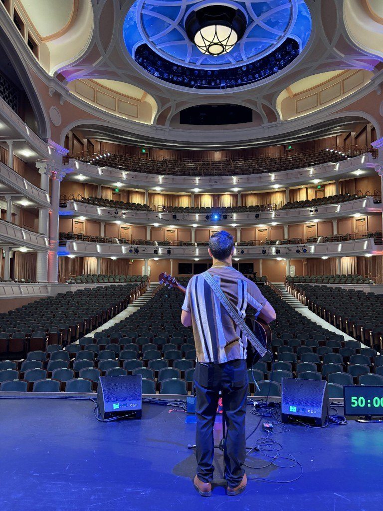 Nicholas Forte with guitar on stage in a theater
